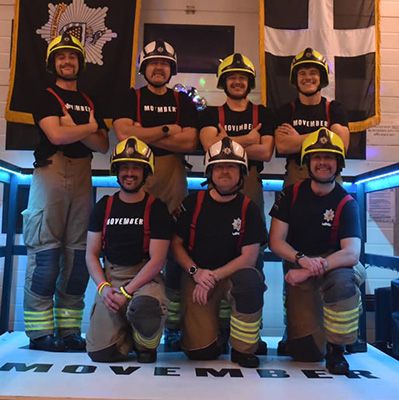 Firefighters in front of flags, posing to camera.