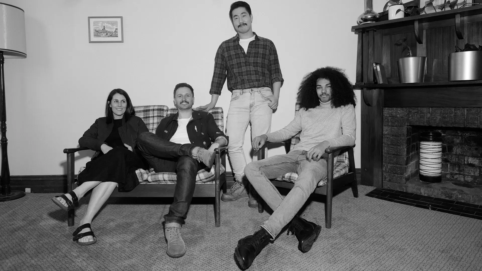 Four smiling friends, sitting together and looking to camera.