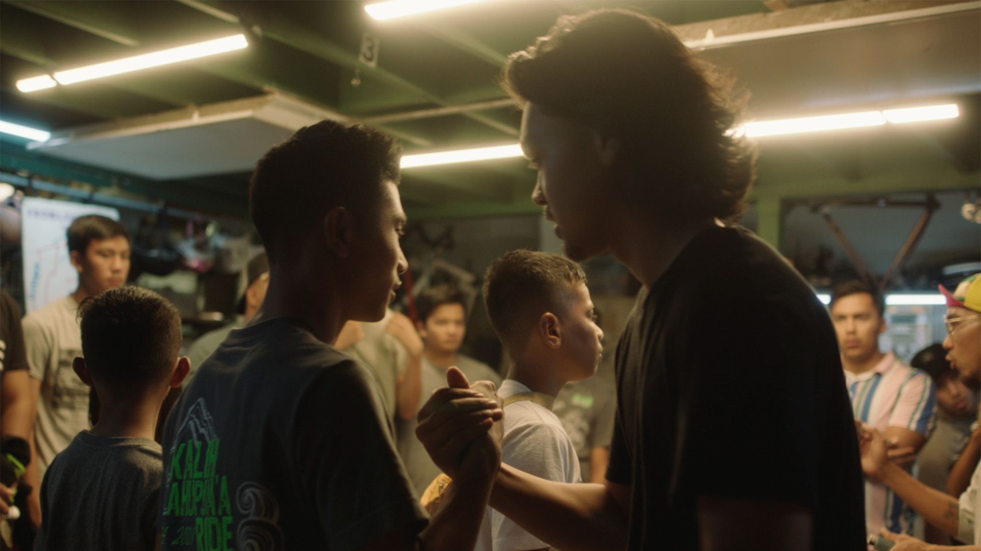 Two young men triumphantly locking arms in a celebratory fashion, in a crowded room.